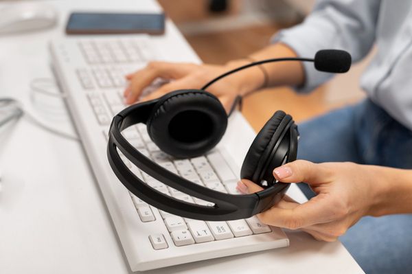 A close-up shot of an employee typing on a keyboard with one hand while   
putting their headphones down with the other following a successful service   
call.